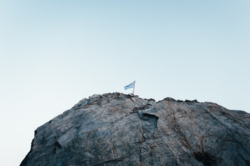 Fototapeta premium Greek flag on a mountain with a blue sky