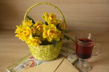 On the table is a yellow basket with flowers of narcotics, a glass cup of tea, a notebook, an envelope.