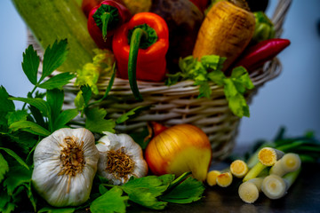 Onion, garlic head and parsley in front of basket full with vegetables