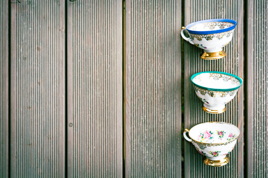 Set of three vintage porcelain tea cups with floral decorations on wooden background