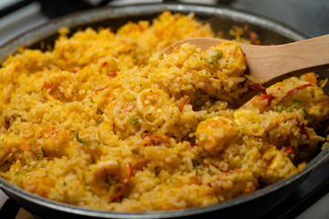 Rice with shrimp, traditional dish of Ecuadorian cuisine, preparation in pan with wooden spoon