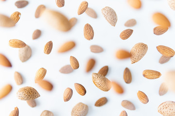 Shelled almond nuts flying above white background, levitation effect