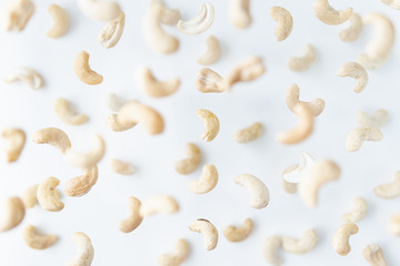 Shelled cashew nuts flying above white background, levitation effect