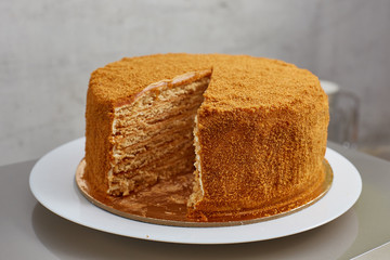 homemade honey cake without a piece. On a white plate in a minimalist style