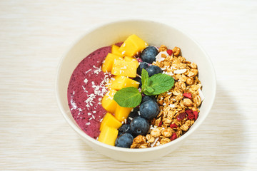 Handmade Bowl healthy tasty breakfast of yogurt, smoothie with granola, nuts, mango and berries.