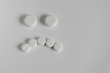 concept of bad medicine. sad face made up of pills on blue backgroud