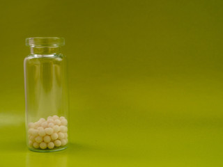 Homeopathic globules and glass bottle on green background. Homeopathic Medicine