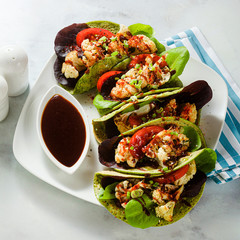 gluten-free vegan green tachos made from chickpea flour with spinach and toppings from baked cauliflower and lettuce with sweet and sour sauce based on soy sauce.
