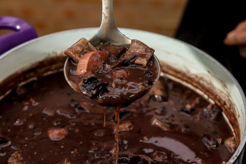 hand holding spoon with brazilian feijoada. 