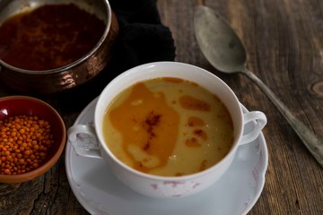 Red Lentil Soup with ingredients on wooden background, top view, copy space. Traditional turkish or arabic lentil and vegetable spicy soup, healthy vegan food.