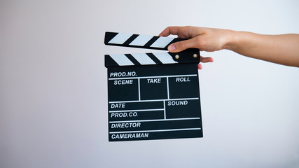 Close up female hold in hand wooden black clapperboard isolated on gray background.