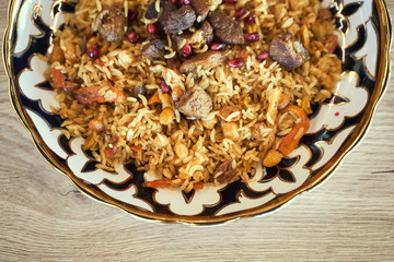 Pilaf in a plate on wooden background, top. A big pilaf pan bowl with mix of vegetables , cooking on the kitchen - 341414864