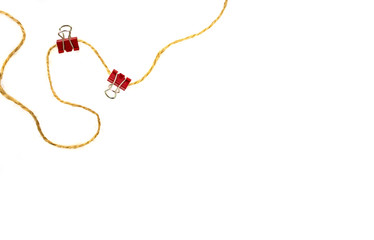 Two red office clips are attached to a string in isolation on a white background: the concept of working in an office