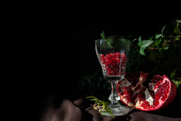 Glass with pomegranate seeds, pomegranate on a black background.