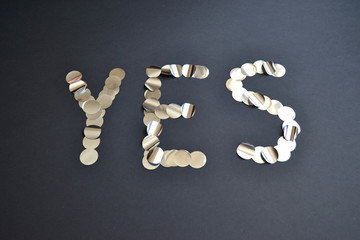 the word yes made of silver confetti on a black background