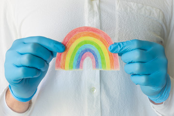 Man in blue medical glove showing the hand drawn rainbow poster. Thank you NHS Staff for your...