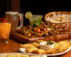 Brazilian snacks on bar table. fried pastry and mixed grilled meat platter. Mug of beer chop and glass in caipirinha. 