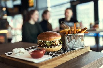 Craft beef burger and french fries on wooden table isolated on black background. Hamburgers and French fries on the wooden tray. - 341419060