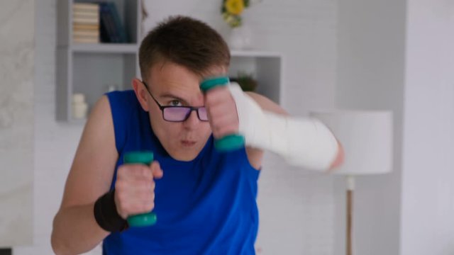 Funny cheerful guy doing sports waving dumbbells at home