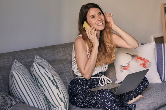 Mujer joven trabajando en casa con su ordenador y su teléfono movil