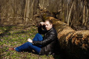 a man sits under a fallen tree in the forest
