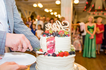 Wedding cake with bride and groom.big white wedding cake with the roses on a white table