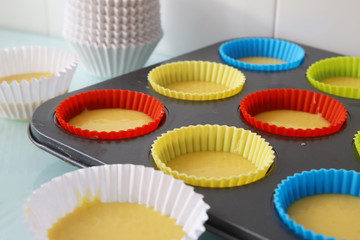 masa para magdalenas en moldes de colores listas para hornear