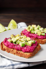 Variation of healthy rye toasts with avocado and beetroot on a plate. Delicious snacks, avocado sandwiches. Food composition, tasty italian meal. Close up