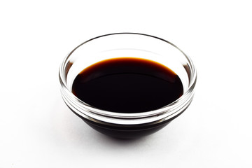 Soy sauce in a glass saucepan on a white plate, isolate