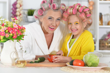 Portrait of senior woman and granddaughter at kitchen