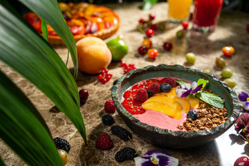 Fruit healthy muesli with peaches strawberry almonds and blackberry in clay dish with yogurt on wooden kitchen table
