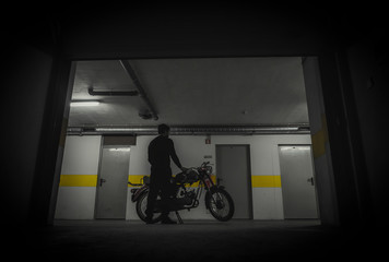 Silhueta de homem e moto antiga na garagem