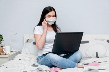 Work Home or Distance Online Learning on Quarantune. Woman in Protective Face Mask Remotely Working on Bed Using Laptop and Talking on Phone