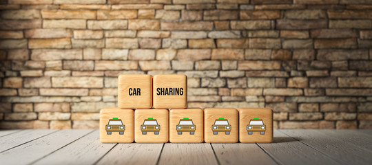 Fototapeta na wymiar cubes with text CAR SHARING and car symbols in front of a brick wall