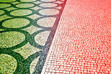 Typical portuguese floor made of small pieces of black and white stone in shape of circles and arcs with the portuguese flag colors (Portugal - Europe)