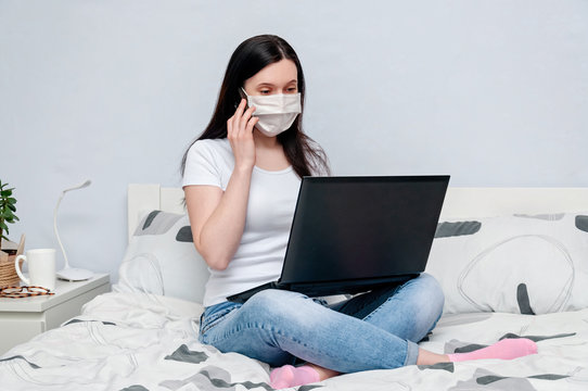Work Home or Distance Online Learning on Quarantune. Woman in Protective Face Mask Remotely Working on Bed Using Laptop and Talking on Phone