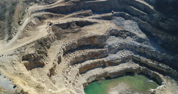 Aerial footage of a steep rock wall at a quarry. It shows mine terraces and landslide