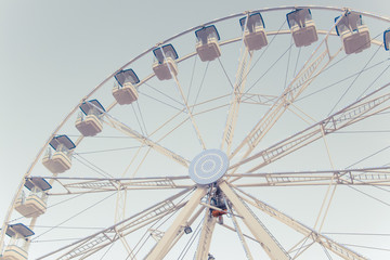 Fototapeta premium A part of ferris and blue sky. Beatiful background with ferris. Blue, light, white, sky, ferris wheel. Ferris wheel and piece sunlight. Vintage style.