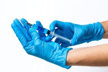 Hands with latex gloves and syringe preparing the coronavirus vaccine