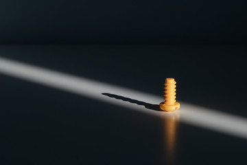 yellow toy plastic small screw in the ray of light casts a shadow