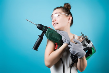 The girl presses an electric drill and a jigsaw to her chest.