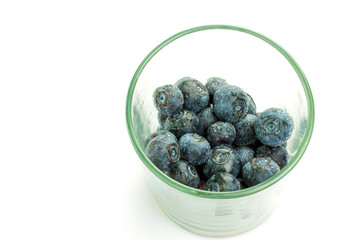 Blueberries in a clear glass on a white isolate.