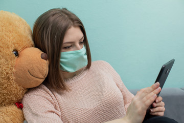 The young girl learns for the exam together with the big teddy bear. They are both wearing...