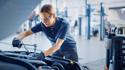 Beautiful Empowering Female Mechanic is Working on a Car in a Car Service. Woman in Safety Glasses...
