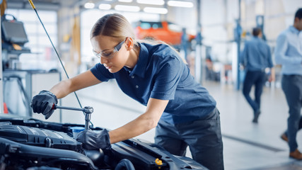 Beautiful Empowering Female Mechanic is Working on a Car in a Car Service. Woman in Safety Glasses...