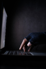 Close up of hacker hand stealing data from laptop 