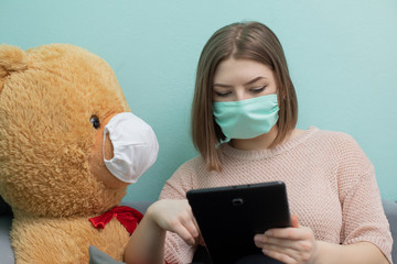 The young girl learns for the exam together with the big teddy bear. They are both wearing...