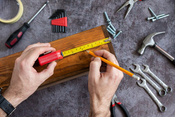 
Measurements using roulette sizes for repair. Hands with tool. Set of tools for home repair. Hammer, pliers, nails, nuts.