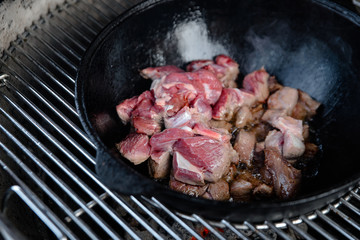 Pieces of lamb with onion are fried in boiling oil on the fire. As a stage in the preparation of...