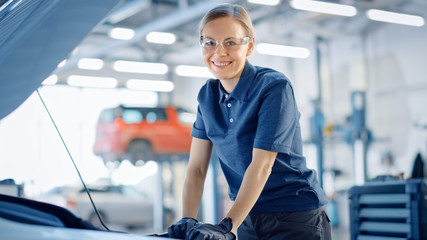 Beautiful Empowering Female Car Mechanic is Working on a Vehicle in a Service. She Looks Happy...
